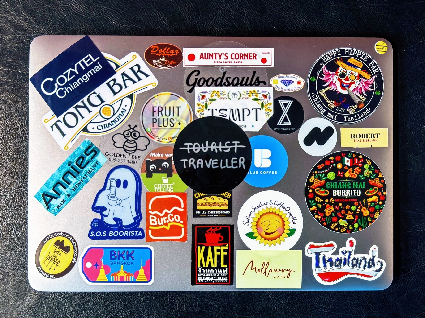 Auto-generated description: A laptop cover is adorned with an assortment of colorful stickers, including those promoting coffee shops, travel destinations, and pop culture references.